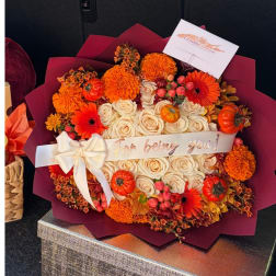 Bouquet of cream roses, orange flowers, and small pumpkins with a ribbon