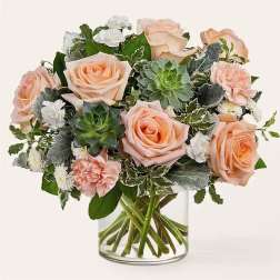 Peach roses and succulents in a clear glass vase