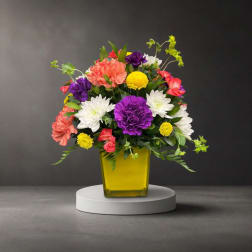 Colorful mixed flower arrangement in a yellow glass vase