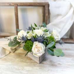 White roses and blue thistle in a wooden box