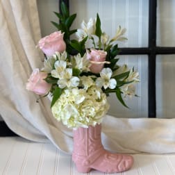 Pink roses and white flowers arranged in a pink boot vase