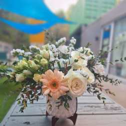 Peach gerbera and white roses in a pink vase
