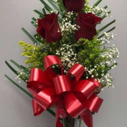 Red roses in a clear vase with a large red ribbon