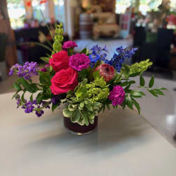 Colorful bouquet of roses, carnations, and blue flowers in a glass vase
