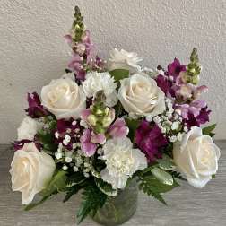 Bouquet of white roses, pink snapdragons, and white carnations in a glass vase