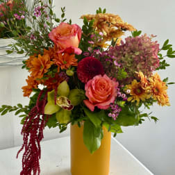 Mixed bouquet of roses, chrysanthemums, and orchids in a yellow vase