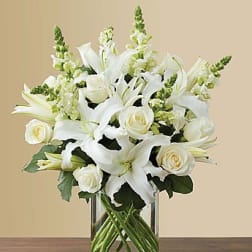 White lilies and roses arranged in a clear glass vase