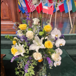 Large floral standing spray with white lilies, roses, orchids, and yellow blooms