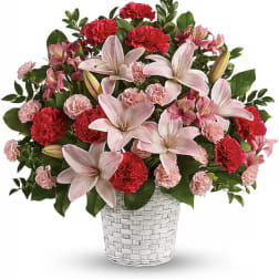 Pink lilies and red carnations arranged in a white woven basket