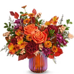 Orange roses and mixed fall flowers in a striped glass vase