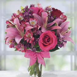 Pink and purple bouquet of lilies, roses, and alstroemeria in a glass vase