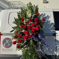 Tall standing spray of red roses and blue flowers with greenery