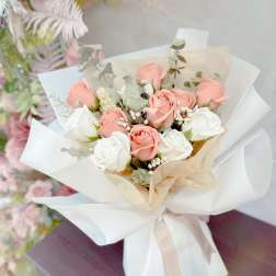 Bouquet of blush and white roses wrapped in white paper
