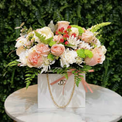 Peach and white flower arrangement in a white gift box with a gold chain handle