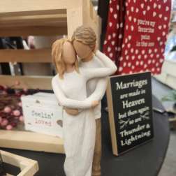 Wooden figurine of a couple embracing beside wedding-themed signs