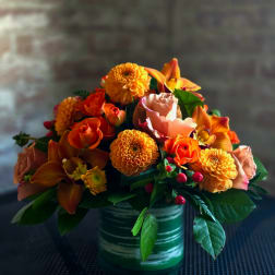 Orange and peach floral arrangement in a green striped vase