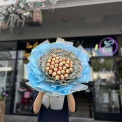 Bouquet of dollar bills and chocolate candies wrapped in blue paper