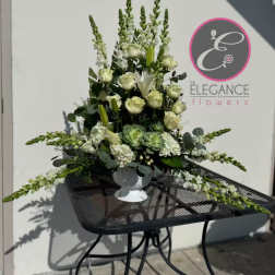 Tall white and green floral arrangement in a white pedestal vase