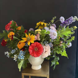 Colorful mixed bouquet in a white vase with zinnias and daisies