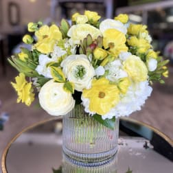 Yellow and white flower arrangement in a clear ribbed vase