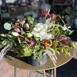 Mixed floral arrangement with white blooms and orange berries in a dark container
