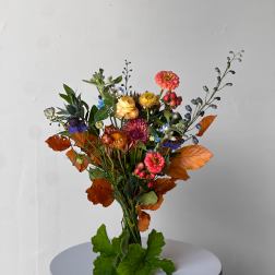 Mixed bouquet with orange, pink, yellow, and blue flowers on a pedestal