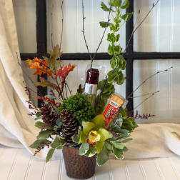 Fall floral arrangement in a textured brown vase with candles and pinecones
