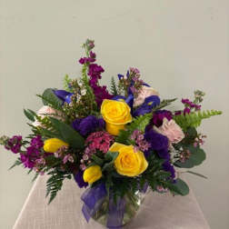 Bouquet of yellow and purple flowers in a glass vase with a ribbon