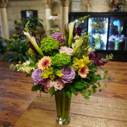 Mixed bouquet in a clear glass vase with roses, calla lilies, and gerbera daisies