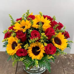 Bouquet of red roses and yellow sunflowers in a clear glass vase