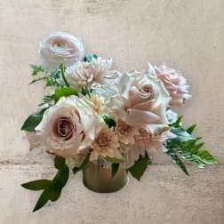 Blush roses and pale daisies arranged in a small vase