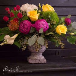 Mixed bouquet of roses, peonies, and calla lilies in a stone vase