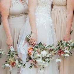 Bride and bridesmaids holding floral bouquets and wreaths