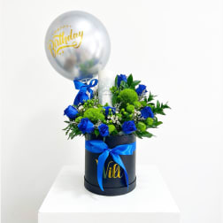 Blue roses and green pompons in a black hatbox with a birthday balloon