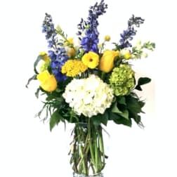 Bouquet of yellow and blue flowers in a clear glass vase