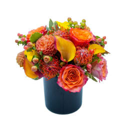 Bright mixed bouquet in a dark vase with orange and yellow blooms