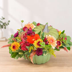 Colorful flower arrangement in a green pumpkin-shaped container