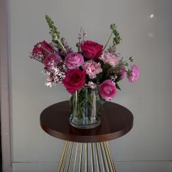 Pink and magenta flowers arranged in a clear glass vase
