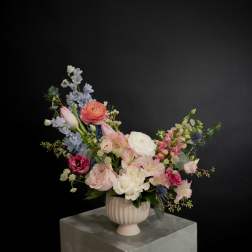 Mixed pink, white, and blue flowers in a ribbed pedestal vase