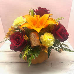 Bouquet of red roses, orange lily, and yellow carnations in a pumpkin container