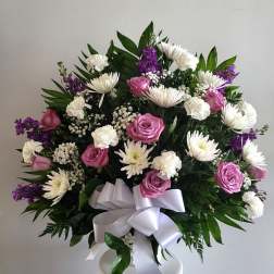 Bouquet of pink roses, white daisies, and purple flowers with a white ribbon