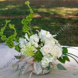 White floral arrangement with roses and lilies in a glass vase
