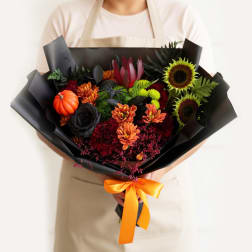 Bouquet of sunflowers, chrysanthemums, and a small pumpkin wrapped in black paper
