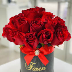 Red roses arranged in a black round box with a red ribbon
