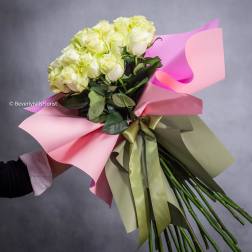 Bouquet of pale yellow roses wrapped in pink paper with a ribbon
