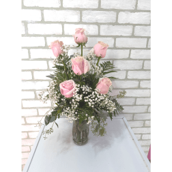 Pink roses arranged in a clear glass vase with baby's breath