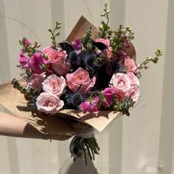 Hand-tied bouquet of pink roses and magenta blooms with dark blue thistles