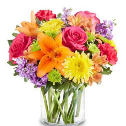 Mixed bouquet of roses, lilies, and daisies in a clear glass vase