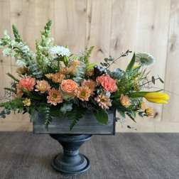 Mixed floral arrangement in a dark wooden container on a pedestal stand