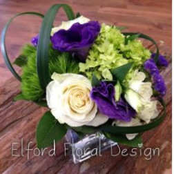 Purple and white floral arrangement with green accents in a clear container